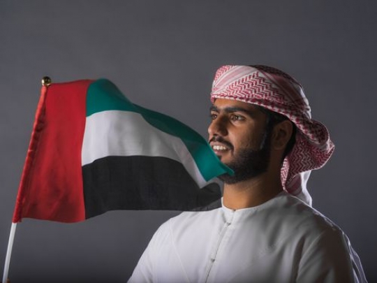 Emirati man holding an Emirati flag|