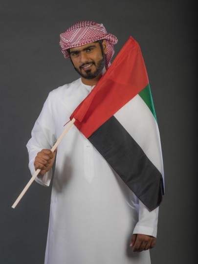 Middle Eastern man smiling carrying the UAE flag |