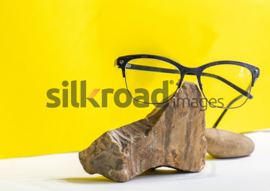Stylish Eyeglasses on Stone with Yellow Background